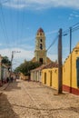 TRINIDAD, CUBA - FEB 8, 2016: View of a cobbled street in the center of Trinidad, Cuba. Bell tower of Museo Nacional de