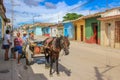 Trinidad,Cuba-November 15,2017.Street city scene with horse as a taxi,man on tricycle,colorful houses,talking Cubans.Lifestyle in Royalty Free Stock Photo