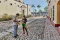 Adult Asian male tourist buying fresh bananas from local black woman on street in Trinidad, Cuba