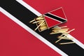 Trinidad and Tobago flag is shown on an open matchbox, from which several matches fall and lies on a large flag