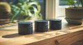 a trio of black containers and some cream on the table