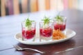 trio of borscht shots in small glasses as an appetizer, garnished with chives