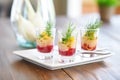 trio of borscht shots in small glasses as an appetizer, garnished with chives