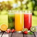 Trio of fresh healthy fruit juice blends in tall glasses on a summer picnic table outdoors with orange