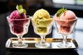 a trio of gelato scoops served in glass dishes