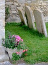 Trio of leaning gravestones seen near the porch of an old church, seen in summertime.