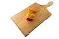 Trio of mini multicolored peppers, aligned on a wooden cutting board, on a white background