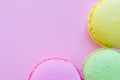 Trio multi colored yellow, pink, green macaroons french cookies on pink background