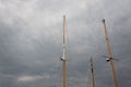 Trio of ship masts, rigging but no sails, against threatening skies with storm clouds Royalty Free Stock Photo