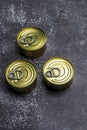 Trio of small metal circular canning tins with easy open pull tabs on gray background