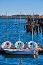 Trio of small white boats on dock with old pilings in background