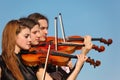 Trio of violinists plays against sky Royalty Free Stock Photo