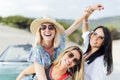 Trio of young Spanish women smiling and laughing on the beach with their car behind them Royalty Free Stock Photo