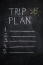 Trip plan list and sun drawing on black chalkboard