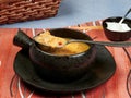 A bowl of tripe soup Romanian: Ciorba de Burta set on a red napkin placed on a blue tablecloth, served with extra cream and a ba