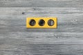 Triple bright yellow frame with power socket, usb ports and light key switch on grey wooden wall Royalty Free Stock Photo