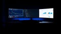 Triple monitor setup displaying financial charts, code, and analytics in a dark room computer Royalty Free Stock Photo