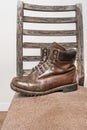 A triple-stitched brown leather hiking boot on an old seat Royalty Free Stock Photo