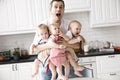 triplets, two boys and a girl in the arms of a happy father. kitchen background