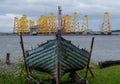 Tripods for supporting wind turbines awaiting relocation, photographed in Cromarty, Scotland, with old blue boat in foreground. Royalty Free Stock Photo