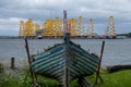 Tripods for supporting wind turbines awaiting relocation, photographed in Cromarty, Scotland, with old blue boat in foreground. Royalty Free Stock Photo