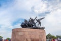 Triumph of Labour statue view with blue sky and clouds in the background and people moving around