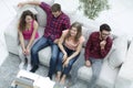 Triumphant group of friends laughing while sitting on the couch in the living room Royalty Free Stock Photo