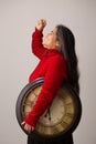 Triumphant Hispanic Woman Holding Clock Raises Fist Into The Air