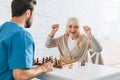 triumphing senior woman celebrating victory and looking at young social worker after Royalty Free Stock Photo