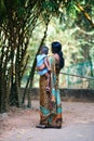 Indian mother wearing sari holds little child on green park background