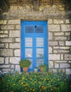 Greece, stone wall house blue window and marigold flowers Royalty Free Stock Photo