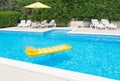 Trogir, Croatia Ã¢â¬â July 13, 2021: Swimming pool with yellow umbrella, chairs for tanning. Yellow air mattress is floating .