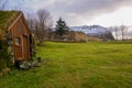 A Troll House In Iceland On A Green Meadow With Snowy Mountains In The Background