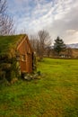 A Troll House In Iceland On A Green Meadow With Snowy Mountains In The Background