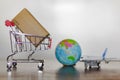 Trolley with carton, airplane and earth globe. International delivery and global logistics concept Royalty Free Stock Photo