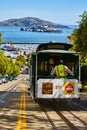 Trolley with driver at back of streetcar going down sunny hill street with Alcatraz Island, CA Royalty Free Stock Photo