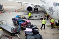 Trolley full of bags, suitcases and other luggage being loaded by ground crew