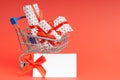 Trolley full of gifts on a red background with mock up and copy space. Concept for christmas, holidays, discounts and shopping