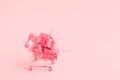 Trolley shopping cart filled with a lot of paper wrapped gift boxes on light background. Toned with pink color Royalty Free Stock Photo