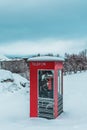 Old red phone box in the snow in Tromso, Norway, now used as a public bookshelf Royalty Free Stock Photo