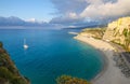 Tropea town and beach, yacht boat in Tyrrhenian Sea, colorful buildings on top of high big rocks, view from Sanctuary church of Royalty Free Stock Photo