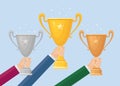 Trophy cup in hand. Gold,silver, bronze goblet isolated on background. Awards for winner, champion. Concept of victory, award, Royalty Free Stock Photo