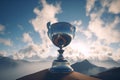 Trophy cup on the mountain peak with blue sky and clouds background Royalty Free Stock Photo