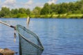 Trophy fishing. Small fish on fishing line, an old fish landing net, sunny landscape with water. Concepts fortune