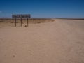 Tropic of capricorn line signage along unpaved road among desert