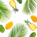 Tropic pattern of pineapple and mango fruits with palm leaves on white background. Flat lay Royalty Free Stock Photo