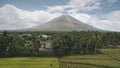 Tropic rural city at palm trees aerial. Mayon volcano countryside with cottages, lodges and fields Royalty Free Stock Photo