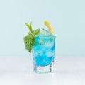 Tropical beach alcohol blue drink  - curacao liquor, lemon slice, ice, mint in misted shot glass on green background. Royalty Free Stock Photo