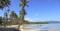 Tropical beach with blue long chairs and palm trees