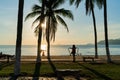 Tropical beach with coconut palm tree in morning sunrise, with people doing exercise with public equipment on Nha Trang beach,